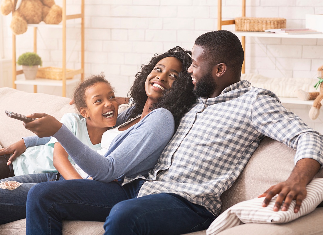 Insurance Solutions - A Joyful Family Having Fun Together While Relaxing on a Sofa at Home